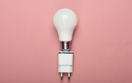 Smart energy-saving light bulb with a charger on pink background. Top viewの写真素材