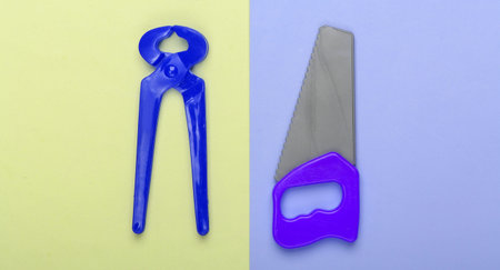 Toy saw and tongs on colored background. Top view