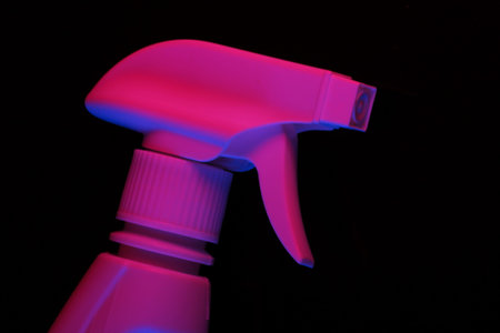 Sprayer bottle head in pink-blue neon light on a black background.