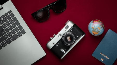 Travel still life. Online booking. Laptop, tourist accessories on a red background. Travel around...