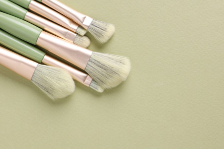 Premium makeup brushes set on green background. Beauty concept