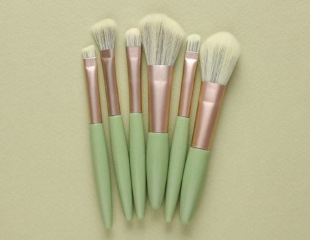 Premium makeup brushes set on green background. Beauty concept
