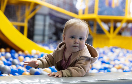Cute little baby plays in a dry pool with balls at a children's entertainment center