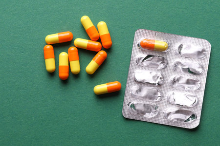 Pills and blister on green background. Medicine concept