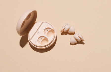 Modern Wireless Bluetooth Vacuum Earbuds with Charging Case on Beige Background with Shadow