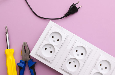 Electrical sockets and electrical plug, Screwdriver and pliers on a purple background. Repair...