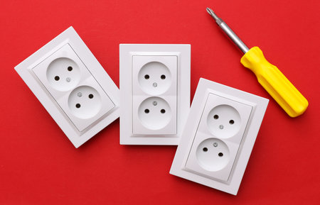Electrical sockets and electrical plug, Screwdriver on red background. Repair concept