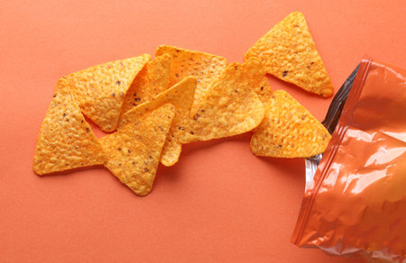 Triangular appetizing corn tortilla chips slices on pink background