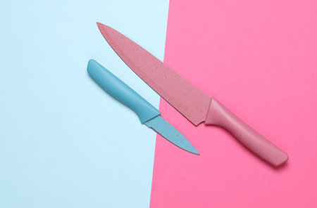 Colored kitchen ceramic knives on pink blue background. Top view. Flat lay