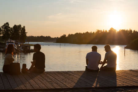 Oulu, Finland - June 2020: people sitting on the waterside, warm evening sunlightのeditorial素材
