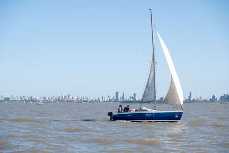 BUENOS AIRES, ARGENTINA - OCTOBER 2018: Couple on a sailboat on Plate river, Rio de la Plata with city skyline in the backgroundのeditorial素材