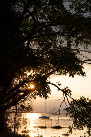 A small boat and sun setting, reflecting in the water at Ibera Wetlands, national park near Colonia Carlos Pellegrini, Corrientes Province, Argentinaの写真素材