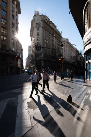 Buenos Aires, Argentina, November 2018 - Urban photo of people walking at Avenida Roque Saenz Pena, or diagonal Norte, San Nicolas neighborhood. They are casting long shadows from the bright, low sunのeditorial素材