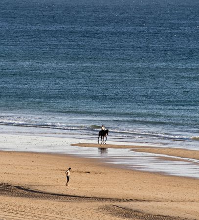 Horsewoman and Jogger at the beach in Andalusienの写真素材