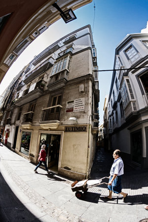 Claus delivering building materials with a small handcart in the narrow streets in Cadiz, Spainのeditorial素材