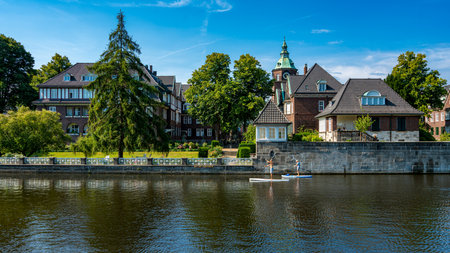 Water sports enthusiasts and excursion boats in the front of expensive luxury properties on the Alster in Hamburg Winterhudeのeditorial素材