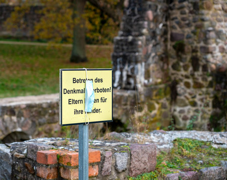 hygiene mask on a sign in front of a ruin in the forestの写真素材