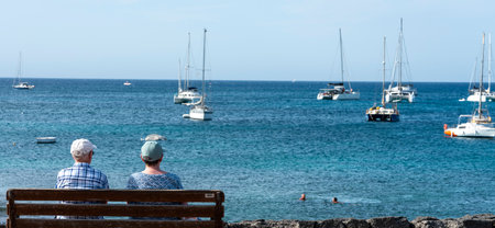 Seniors sitting on a wooden bench by the sea, Lanzarote, Canary Islands, Spainのeditorial素材