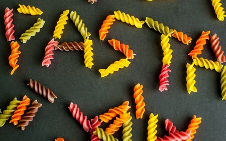 Word pasta made of color fusilli on black backgroundの写真素材