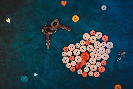 Sewing buttons in the shape of a heart with vintage keys on a retro blue backgroundの写真素材