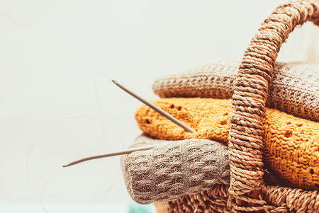 Stack of cozy knitted sweaters in a wicker basketの写真素材