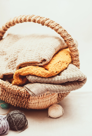 Stack of cozy knitted sweaters in a wicker basket
