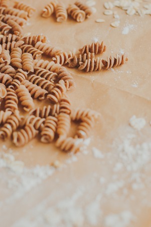 wholemeal pasta fusilli from organic whole grain spelt falling from a paper bag