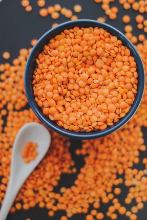 Red raw lentil in bowl on black backgroundの写真素材