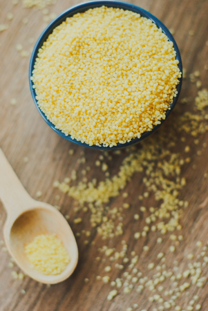 Raw couscous in the bowl on wooden backgroundの写真素材