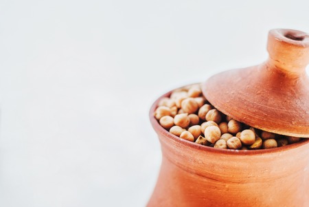 uncooked chickpeas in a rustic clay bowl on white backgroundの写真素材