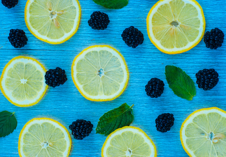 Colorful bright pattern of leaves, blackberries and lemon on blue backgroundの写真素材