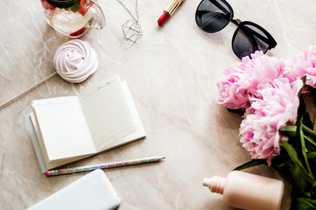 Beauty flat lay with a diary, smartphone, accessories and peonies on a marble background. Top viewの写真素材