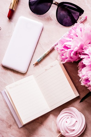 Beauty flat lay with a diary, smartphone, accessories and peonies on a marble background. Top viewの写真素材