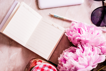 Beauty flat lay with a diary, smartphone, accessories and peonies on a marble background. Top viewの写真素材