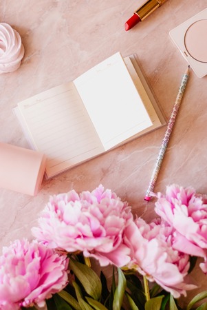 Beauty flat lay with a diary, smartphone, accessories and peonies on a marble background. Top viewの写真素材