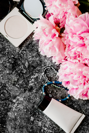 Beauty flat lay with accessories, perfume, cosmetics and peonies on a dark marble background. Top viewの写真素材