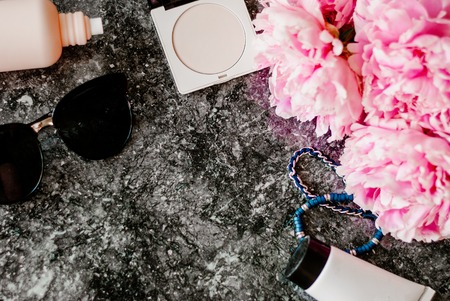 Beauty flat lay with accessories, perfume, cosmetics and peonies on a dark marble background. Top viewの写真素材