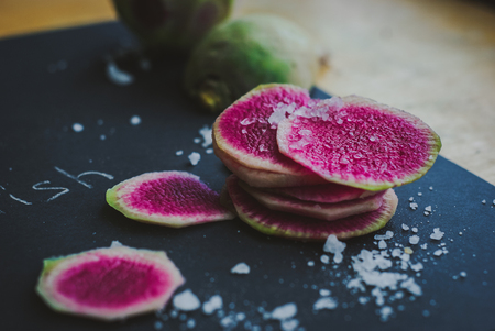 Watermelon Radishes Sliced, Sprinkled with Sea Salt on a black backgroundの写真素材