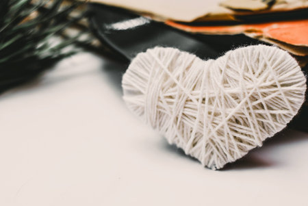 white knitted heart and stack of scratched dusty old vinyl records tied with rope on white backgroundの写真素材