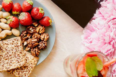 Office employee with laptop, healthy snack, water with strawberry and cucumber. Having strawberries, peanut, walnut, crispbread while working.の写真素材
