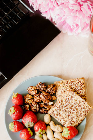 Office employee with laptop, healthy snack, water with strawberry and cucumber. Having strawberries, peanut, walnut, crispbread while working.の写真素材