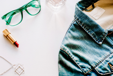 Blue jeans jacket, necklace, perfume and green glasses top view. Flat lay photo.の写真素材