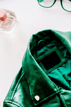 Green leather jacket and sunglasses on white background. Alternative fashion set. Flat lay, top view.の写真素材