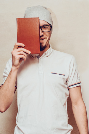 Portrait of handsome bearded man wearing glasses white shirt, reading book. Horizontal, film effect.の写真素材
