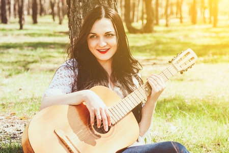 woman playing an acoustic guitar outdoorの写真素材