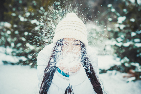 brunette woman is happy and blowing snow in the natureの写真素材