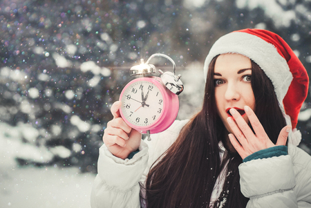 Smiling surprised woman in claus hat holding alarm clockの写真素材