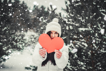 Beautiful young woman holding a red heart in the hands.の写真素材