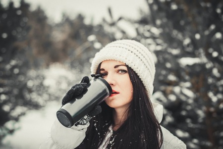 very positive woman pours tea in winter park . Young woman winter portrait.の写真素材