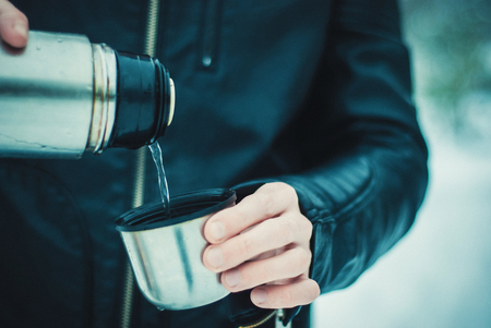 Photo of concentrated bearded man wearing hat holding flask in handsの写真素材